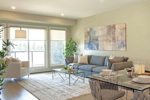 A modern living room with a glass table and grey couches.