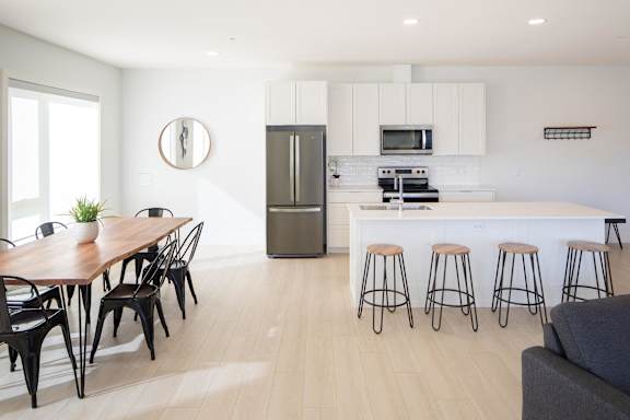 A modern kitchen with a dining table and bar stools.