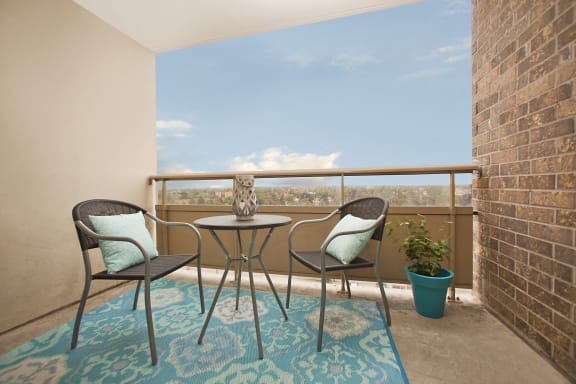 a balcony with two chairs and a table and a brick wall