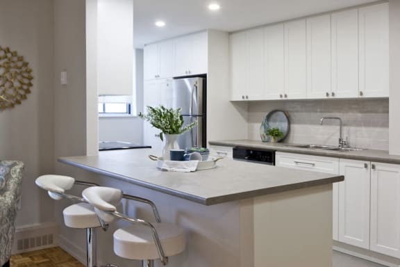 a modern kitchen with white cabinets and a counter with two white chairs