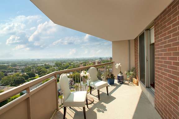 A balcony with two chairs and a table with a vase of flowers on it.