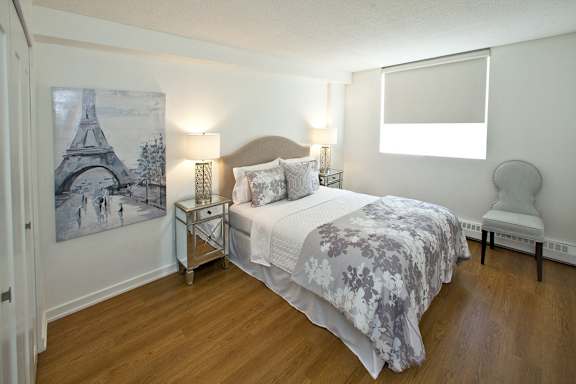 A bedroom with a bed, nightstand, and chair.