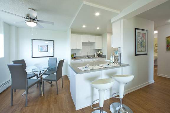 A modern kitchen with white cabinets and a glass table.