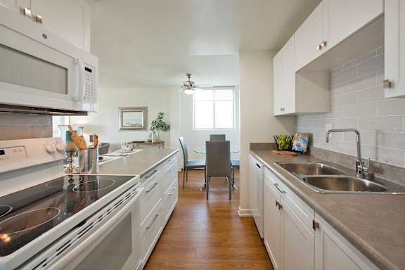 A kitchen with white cabinets and a grey counter top.