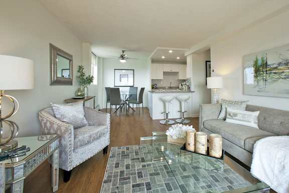 A modern living room with a glass coffee table and grey couches.
