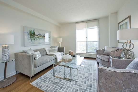 A living room with a grey couch and a glass coffee table.