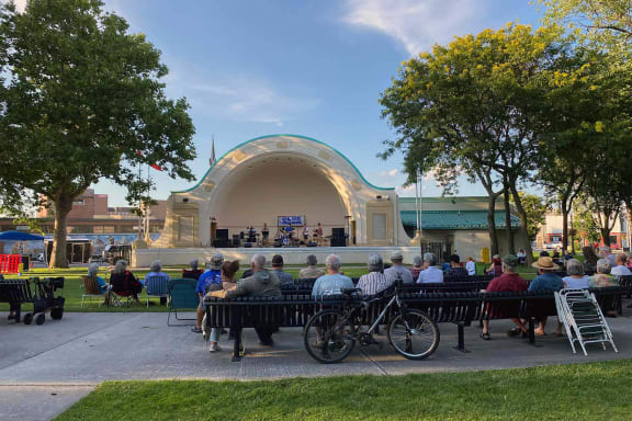 people sitting on benches watching a band play on a stage