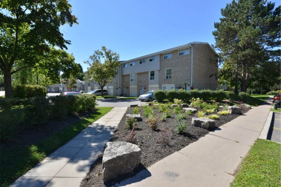 the front of an apartment building with a garden in front of it