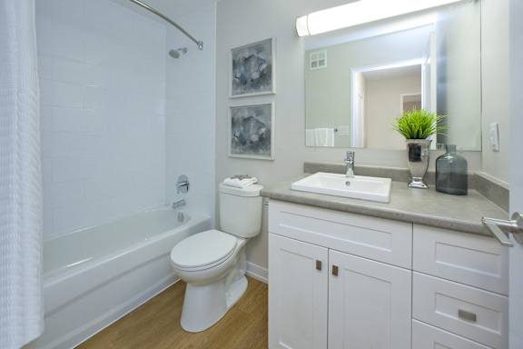 A white toilet in a bathroom with a white tub and a white sink.