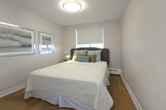 A bedroom with a bed, pillows, and pictures on the wall.