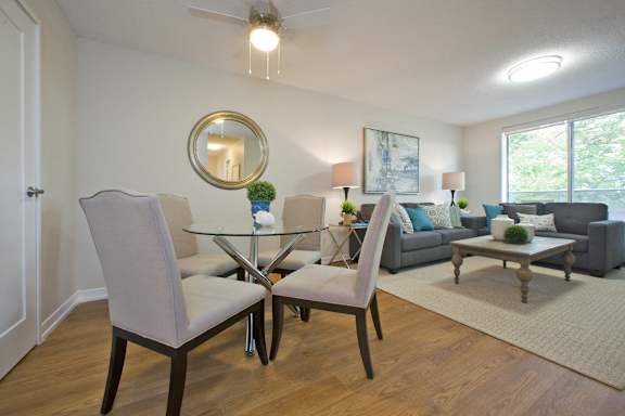 A living room with a glass table and grey chairs.