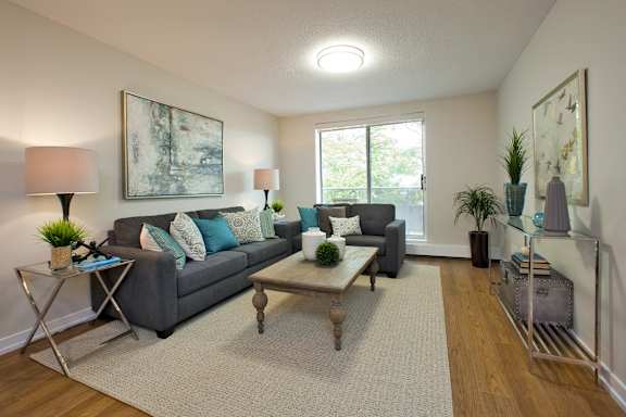 A living room with a grey couch, a coffee table, and a painting on the wall.