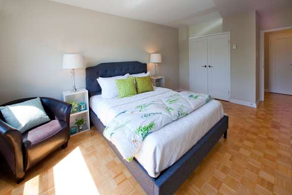 A bedroom with a large bed and a chair.