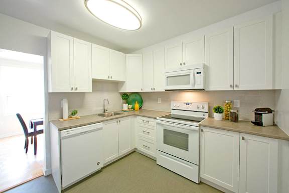 A white kitchen with a microwave on the counter.