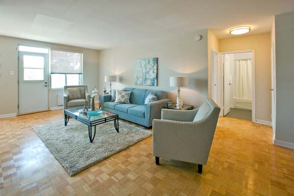 A living room with a blue couch and a glass coffee table.