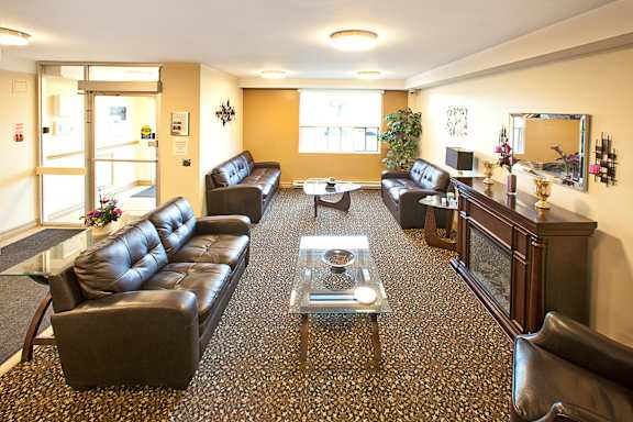 A living room with a black leather couch and a glass coffee table.