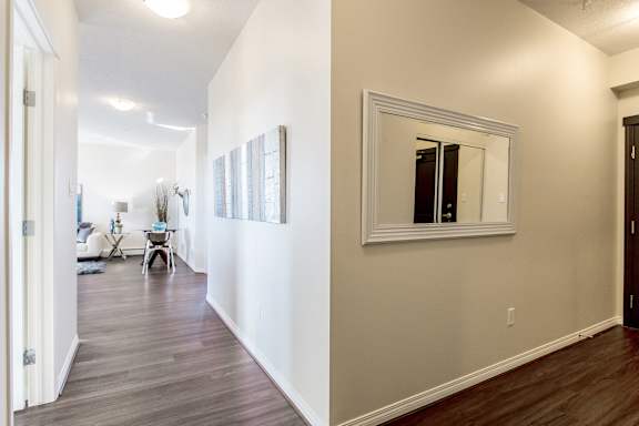 a living room and hallway with wood floors and a mirror