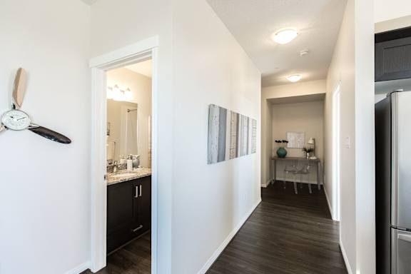 a corridor with a kitchen and a hallway with a refrigerator and a sink