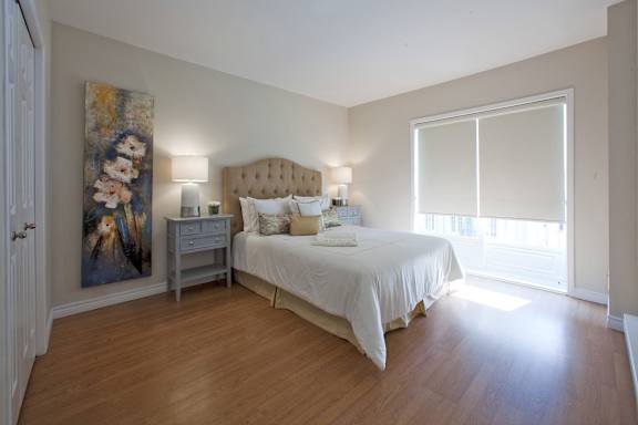 A bedroom with a large bed and a painting on the wall.