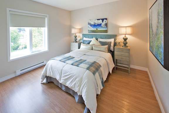 A bedroom with a bed, nightstands, and a painting on the wall.