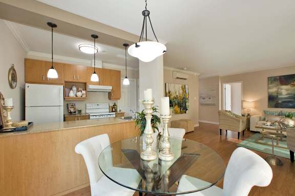 A modern kitchen with a glass table and white chairs.