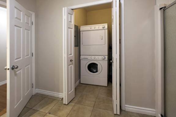 A white door is open to a small laundry room with a washer and dryer.