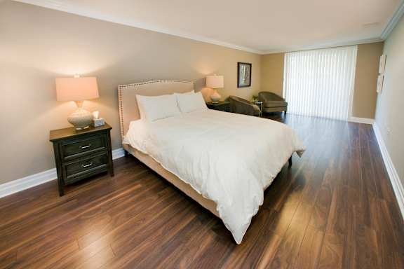 A bedroom with a large bed and wooden floors.