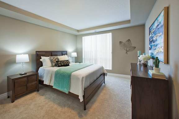 A bedroom with a bed, nightstand, and a painting on the wall.