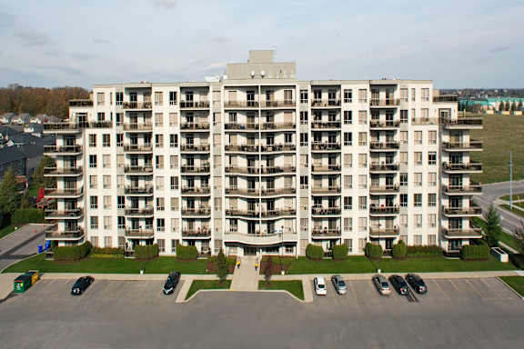 A large white apartment building with a parking lot in front.