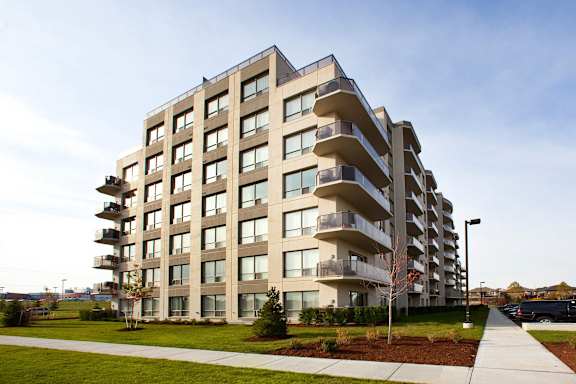 A modern apartment building with balconies on the upper floors.