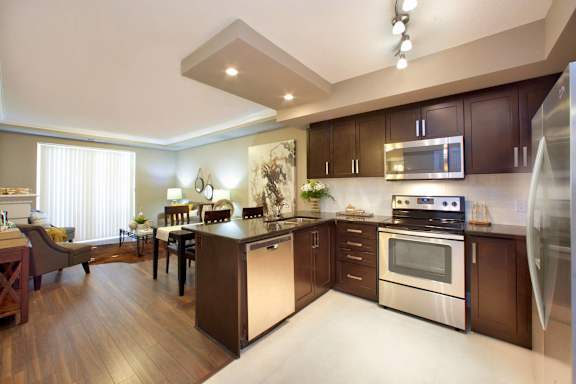 A modern kitchen with dark wood cabinets and stainless steel appliances.