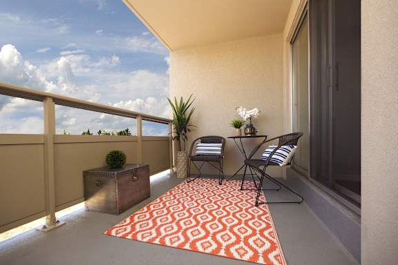 A balcony with a table and chairs and a potted plant.