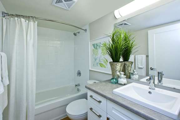 A white bathroom with a white toilet, a white sink, and a white shower curtain.