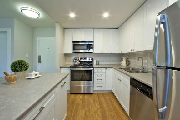 A modern kitchen with stainless steel appliances and wooden floors.