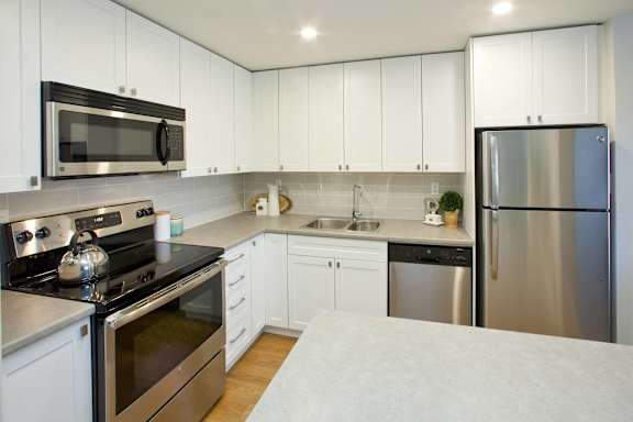 A modern kitchen with stainless steel appliances and white cabinets.