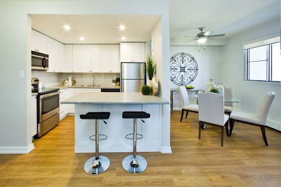 A kitchen with a bar and chairs.