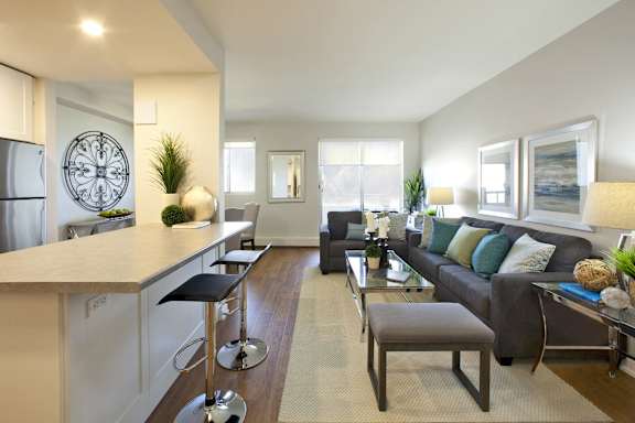 A modern kitchen with a bar and a living room with a couch.