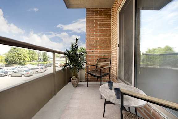 A balcony with a table and chairs overlooking a parking lot.