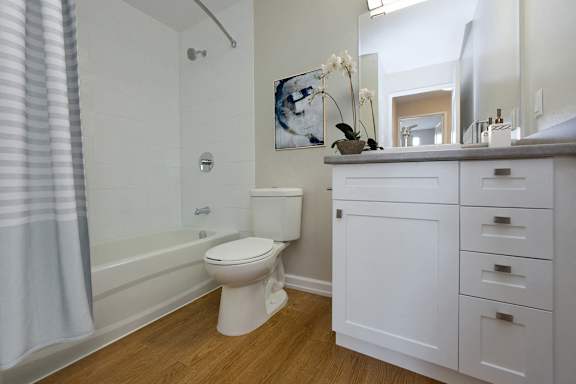 A white toilet sits in a bathroom next to a white cabinet.