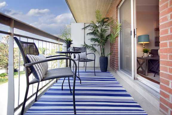 A balcony with a blue striped carpet and a black chair.