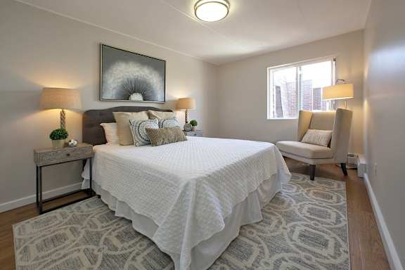 A bedroom with a large bed and a chair.