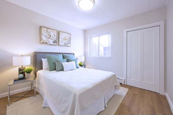 A bedroom with a bed, nightstand, and two framed pictures on the wall.