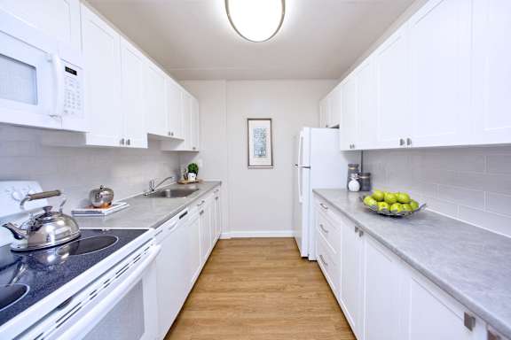 A kitchen with white cabinets and a stove top oven.