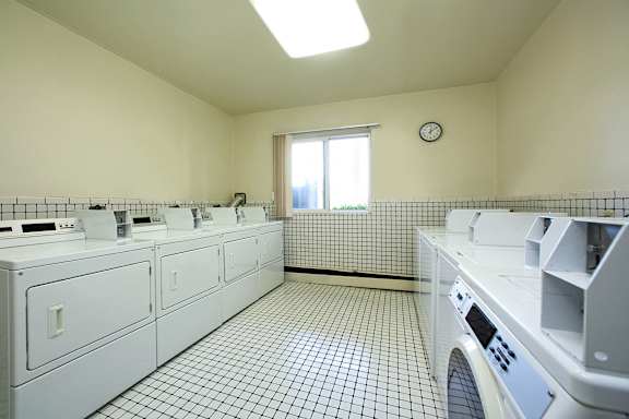 A laundry room with a washer and dryer on the right and a window on the left.