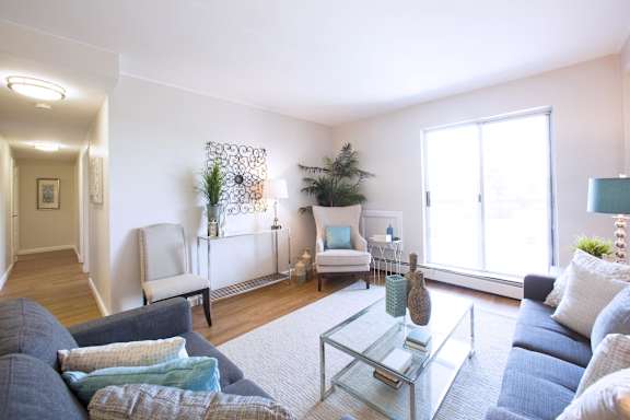 A living room with a grey couch and a glass coffee table.