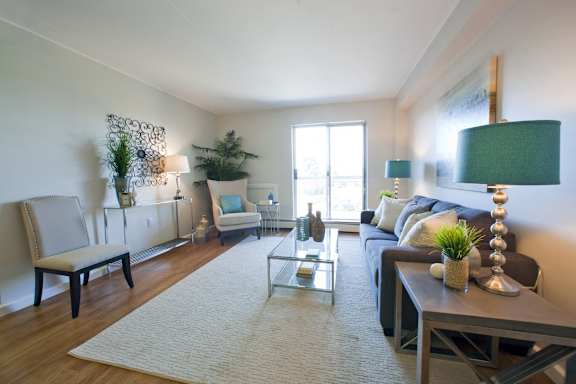 A living room with a couch, chair, and potted plants.