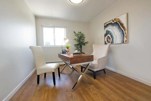 A dining room with a wooden table and white chairs.