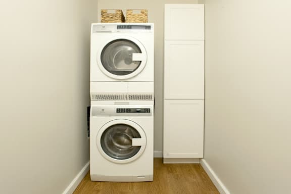 A white washing machine and dryer stacked on top of each other in a small room.