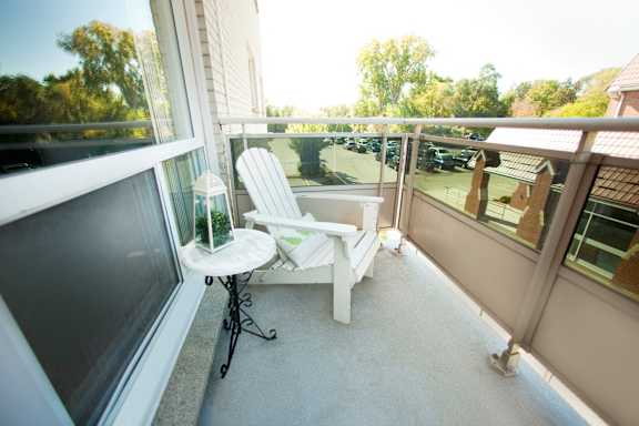 A white chair is on a balcony with a table and a plant.