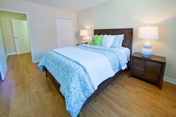A bedroom with a bed, nightstand, and two lamps.
